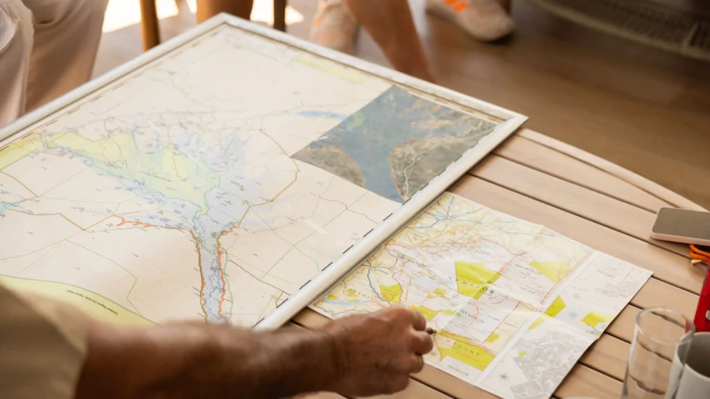 Tourist guide pointing to a detailed map of the Okavango Delta while explaining the route during a houseboat journey.