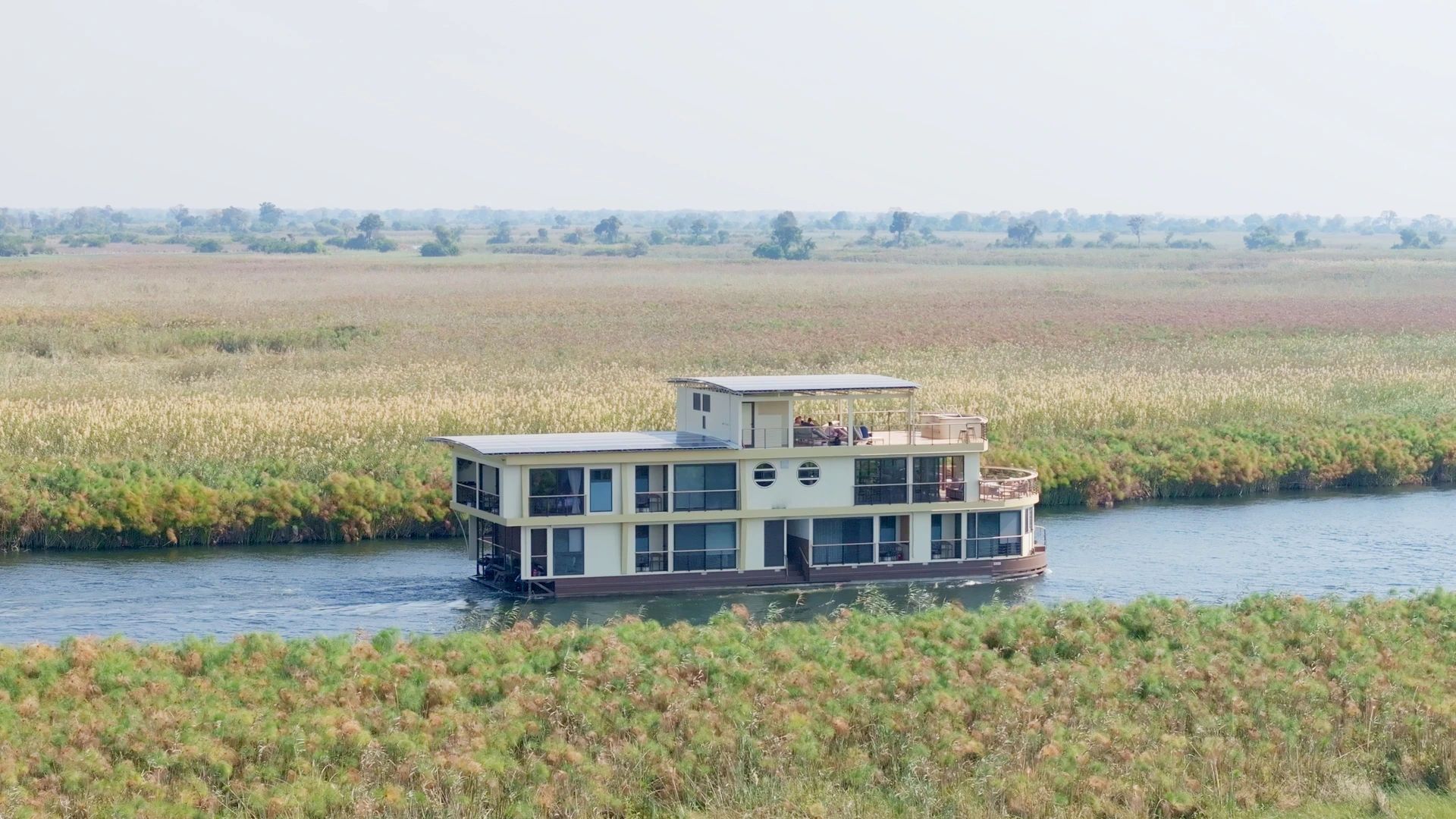 The Okavango Endeavour houseboat beside reed beds on a delta channel